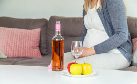 A pregnant woman drinks wine in a glass. selective focus. food.の写真素材