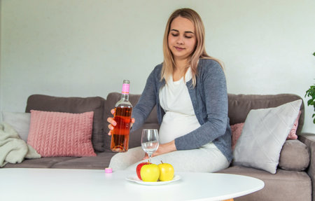 A pregnant woman drinks wine in a glass. selective focus. food.の写真素材
