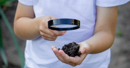 the child holds the earth in his hand and looks through a magnifying glass. selective focusの写真素材