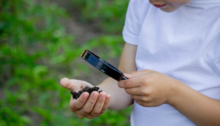 the child holds the earth in his hand and looks through a magnifying glass. selective focusの写真素材
