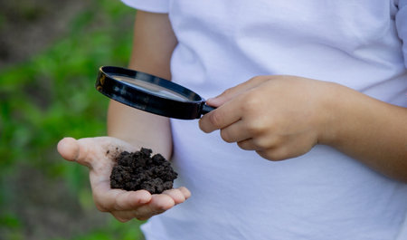 the child holds the earth in his hand and looks through a magnifying glass. selective focusの写真素材