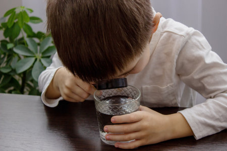 the child looks at the water through a magnifying glass. selective focus. Natureの写真素材