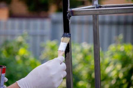 a man paints metal with black paint with a brush. selective focusの写真素材