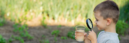The child boy looking at water in a glass through magnifying glass. selective focus. natureの写真素材