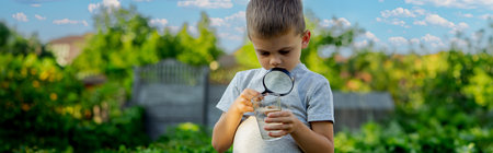 The child boy looking at water in a glass through magnifying glass. selective focus. natureの写真素材