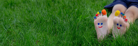 a boy on the grass with a painted smile on his feet.. Selective focus. nature