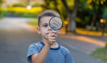 boy looks into a magnifying glass. Selective focus. Natureの写真素材