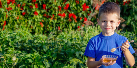 boy eats honey in a flower garden. Selective focus. Natureの写真素材