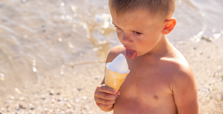 little boy eating ice cream on the beach on vacation. seaの写真素材