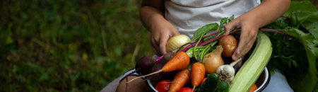 hands of a child farmer vegetables in a bowl in the gardenの写真素材