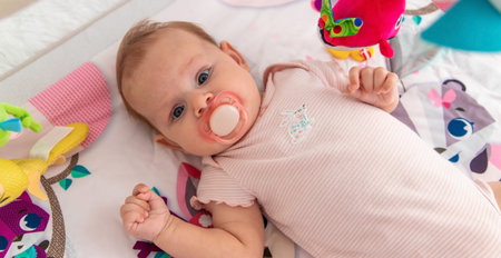 a baby plays with hanging toys on a play mat. a child, a baby plays at home.
