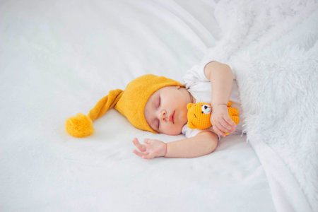 a baby in a white bodysuit is sleeping on a white background, hugging a bear. childの写真素材