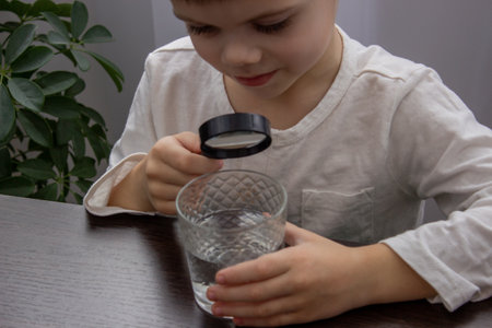 A child looks at the water through a magnifying glass. Selective focus.の写真素材