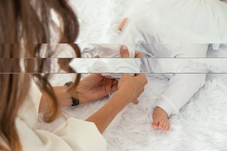 a woman dresses a baby in white clothes.