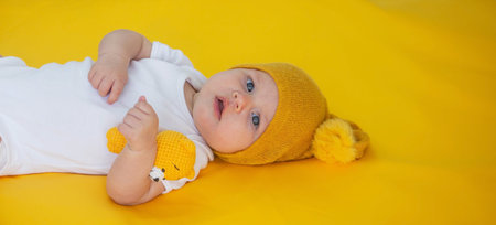 smiling baby girl goes to sleep with a teddy bear on a yellow background. children