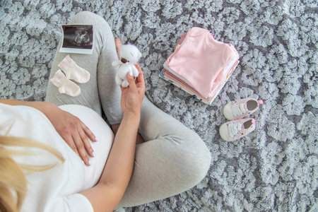 A pregnant woman collects baby things. Selective focus. Home.