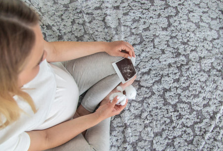 A pregnant woman collects baby things. Selective focus. Home.