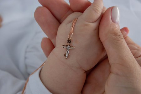 The sacrament of baptism of a child. The child is holding a crossの写真素材