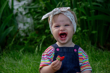 little girl eating strawberries in the garden. Selective focus.の写真素材