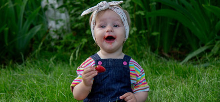 little girl eating strawberries in the garden. Selective focus.の写真素材