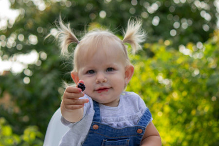 little happy girl eating blackberry. Selective focus.