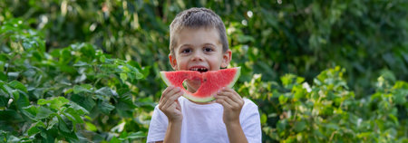 boy eats watermelon on the background of nature. Selective focus.の写真素材