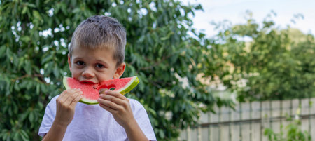 boy eats watermelon on the background of nature. Selective focus.の写真素材