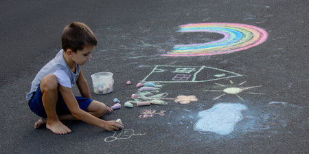 the boy draws with chalk on the asphalt. Selective focus.の写真素材