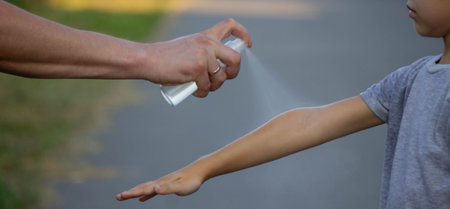 a man applies insect repellent to his son's hand in a park, close-up. Prevention of bites.の写真素材