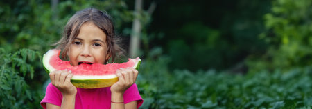 little girl eats healthy organic watermelon in the garden, nature background.の写真素材