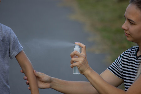 woman applies insect repellent to her son's hand in the park, close-up. Prevention of bites.の写真素材