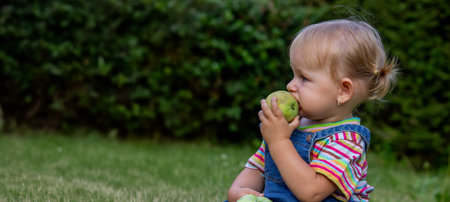 little girl with apples in the gardenの写真素材