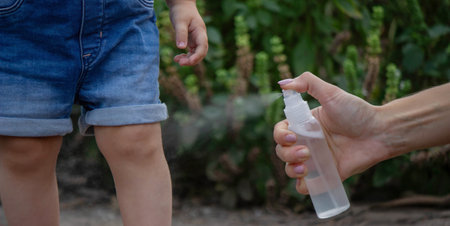 mother applies an aerosol insect spray to the child's body. Selective focus.の写真素材