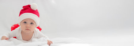 Baby girl in a Santa hat on a light background.holidayの写真素材