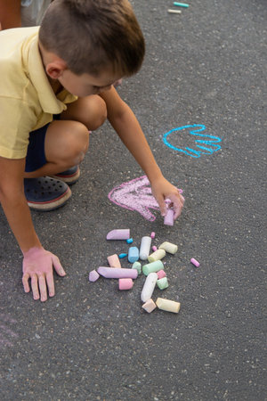 boy draws on the asphalt with chalk. Selective focus.の写真素材