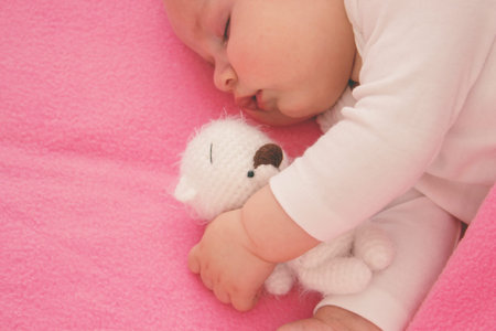 Baby sleeping on a pink background with a pink teddy bear.child.の写真素材