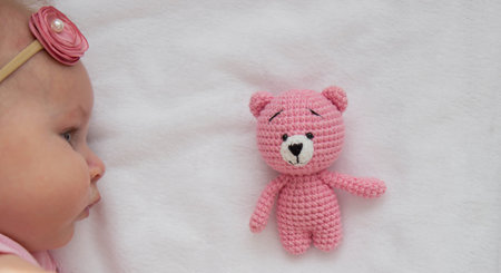A baby in a pink dress lies with a pink teddy bear on a white background.baby.の写真素材