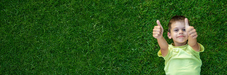 Smiling and happy boy lying on green grass. Childrenの写真素材