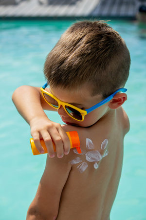 smiling boy wearing glasses and sunscreen with a sun painted on his shoulder. sun protection.