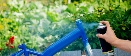 Spray Painting a Bicycle Frame Outdoors.