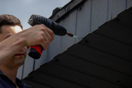 Man Installing Roof Panels with a Drill.の写真素材