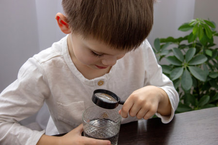 little boy looking at water through a magnifying glass, water analysis. Selective focusの写真素材