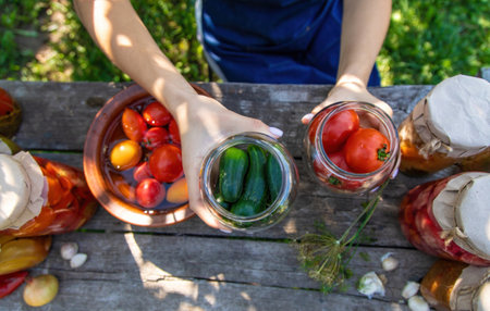 woman canning tomatoes cucumbers vegetables on the background of nature. Selective focus.の写真素材