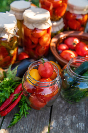 woman canning tomatoes cucumbers vegetables on the background of nature. Selective focus.の写真素材