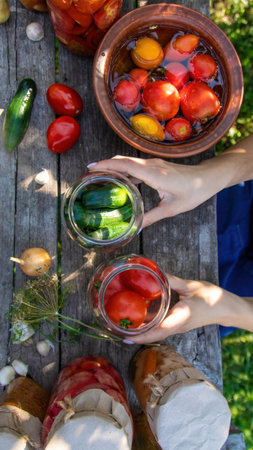 woman canning tomatoes cucumbers vegetables on the background of nature. Selective focus.の写真素材