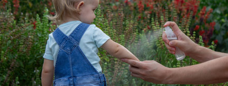 mother applies an aerosol insect spray to the child's body. Selective focus.