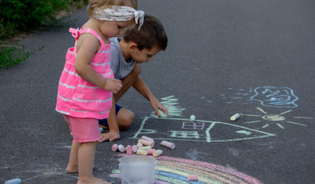 The child draws with chalk on the asphalt. Selective focus. Kid.