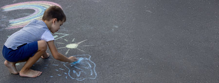 The child draws with chalk on the asphalt. Selective focus. Kid.の写真素材