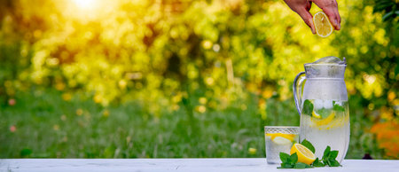 Glass of lemonade with lemons and fresh mint, on a light background in the gardenの写真素材