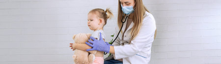 Female doctor examining little girl, listening to lungs with stethoscope. Pediatrician's...
